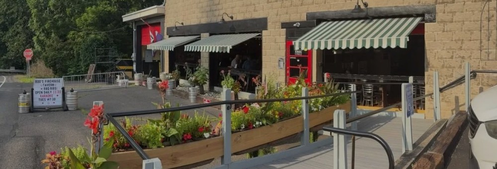 Outdoor restaurant seating with striped awnings and flower boxes along a ramp.