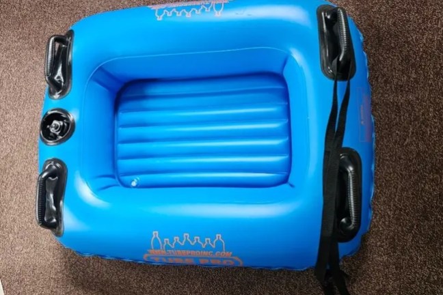 Blue inflatable raft with black handles on a brown carpet