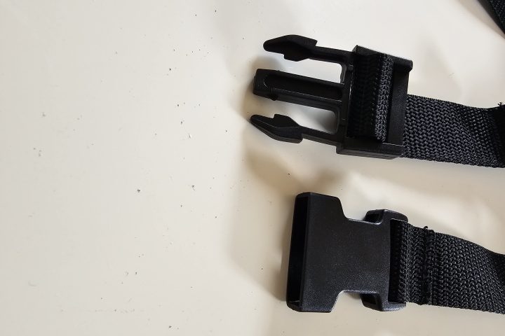 Black plastic buckle on a white background, partially unfastened.